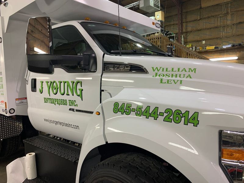 White J Young Disposal Inc. truck with green lettering; phone number 845-544-2614.