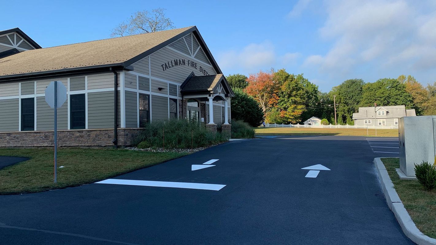 Building with angled roof, windows, and arrows painted on asphalt directing traffic.