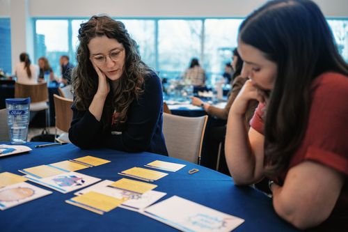 Two people review papers at a blue table in a bright conference room.