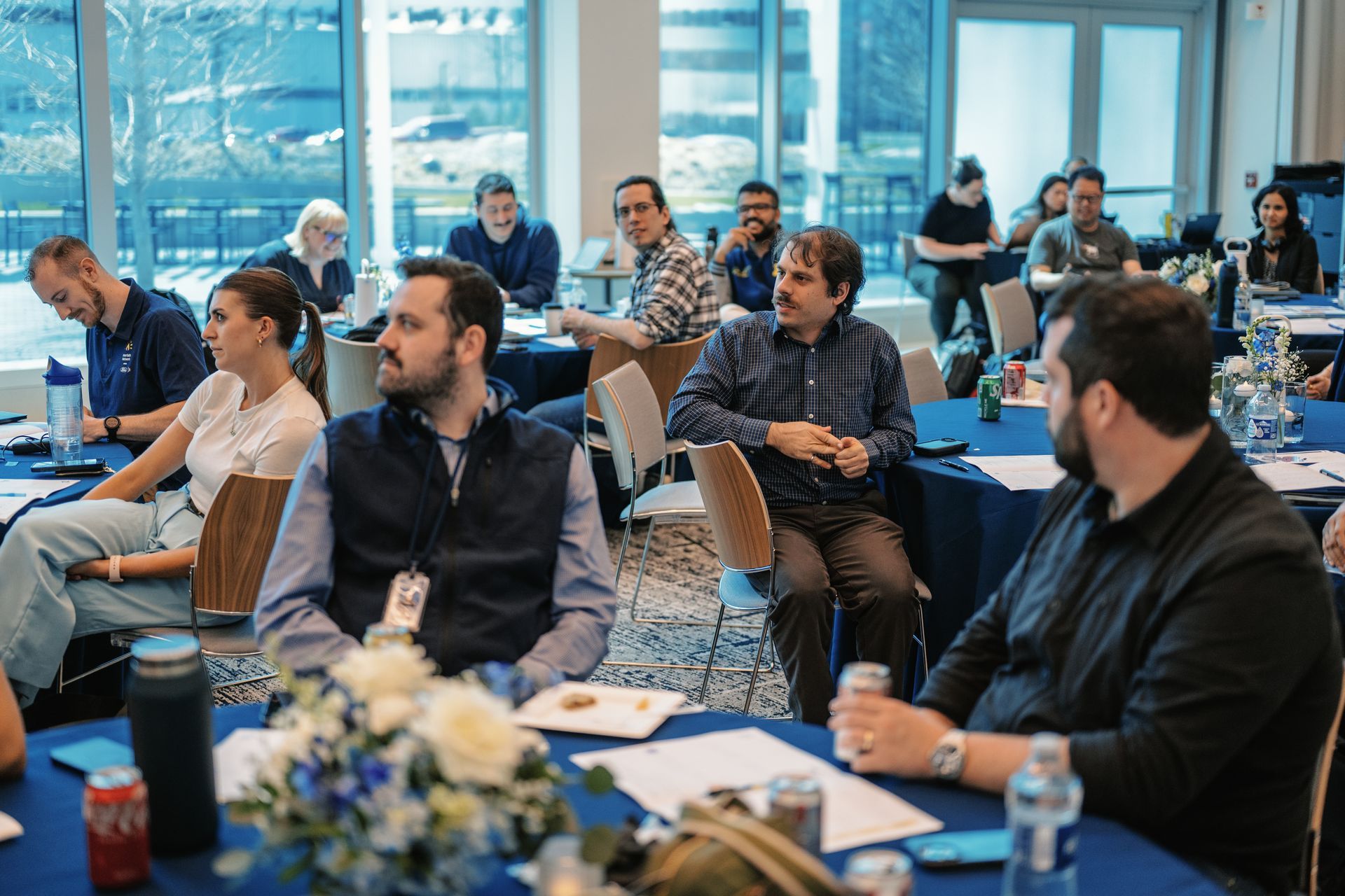 Audience seated in a bright conference room, listening during a presentation.