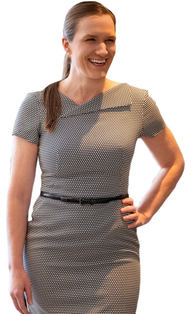 Smiling person in a patterned dress with hand on hip, standing against a white background
