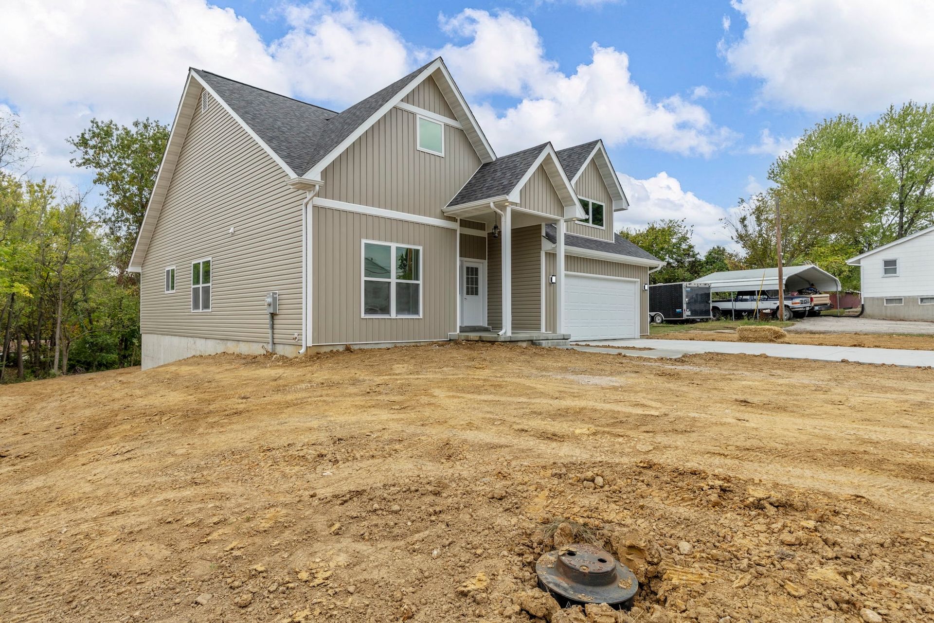 New gray house with unfinished dirt front yard under a blue sky