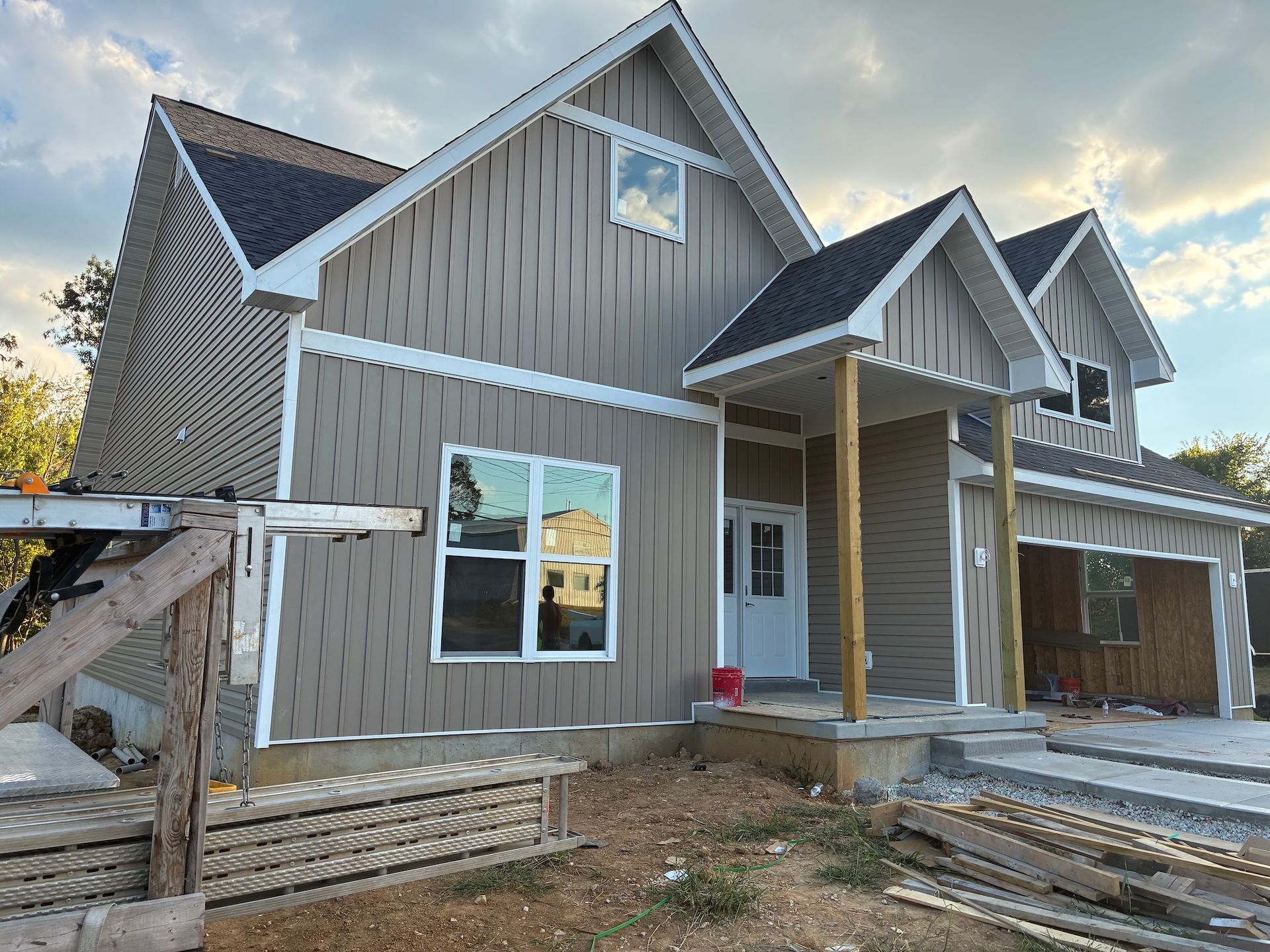 New gray house under construction with white trim and front porch