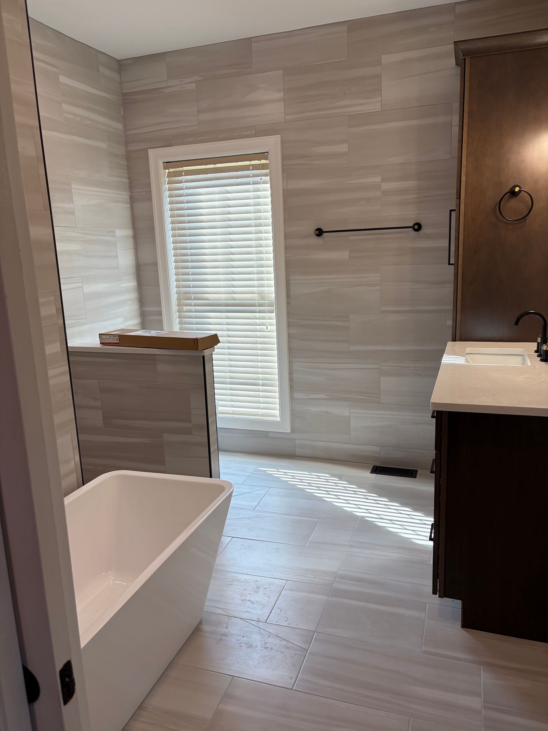 Bathroom with freestanding tub, walk-in shower, vanity, and window blinds.
