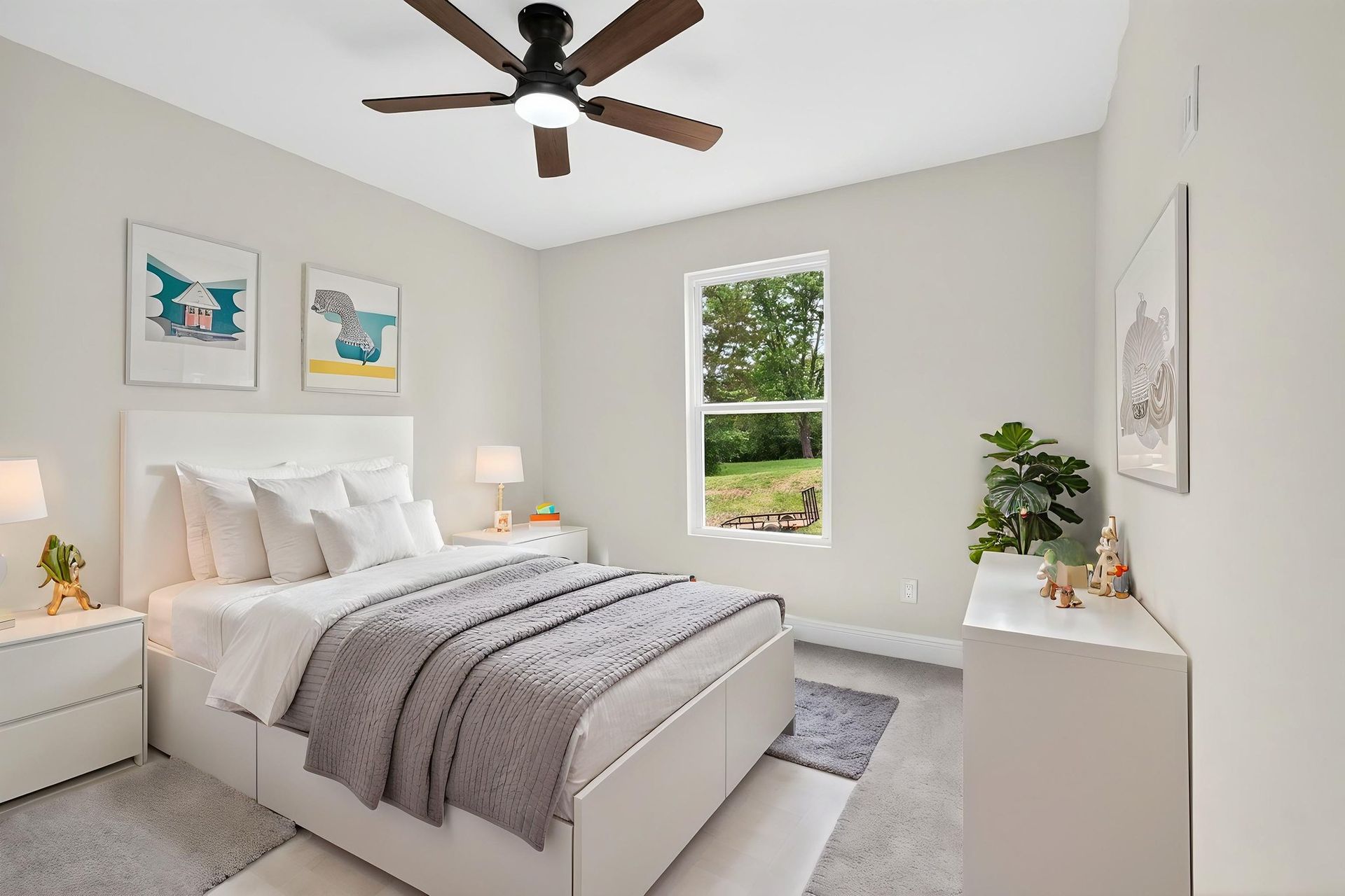 Bright bedroom with white bedding, gray blanket, ceiling fan, and framed wall art