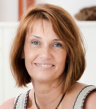 Eine Frau mit braunen Haaren und blauen Augen lächelt für die Kamera