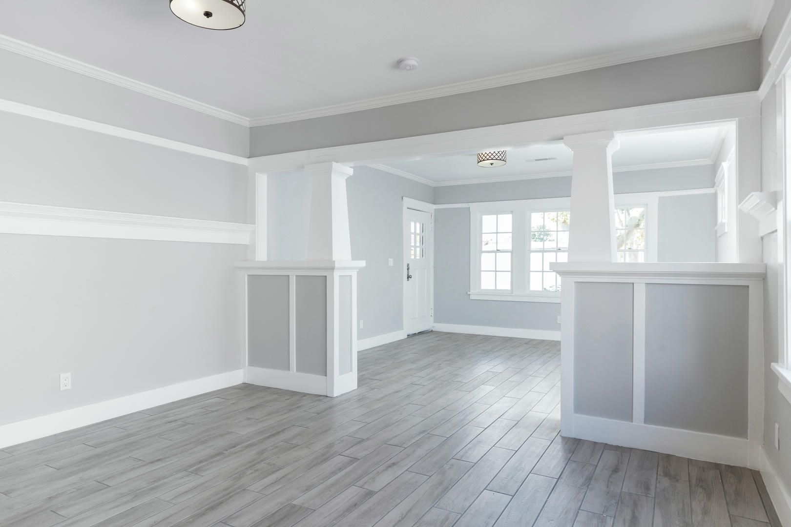 An empty living room with hardwood floors and white walls.