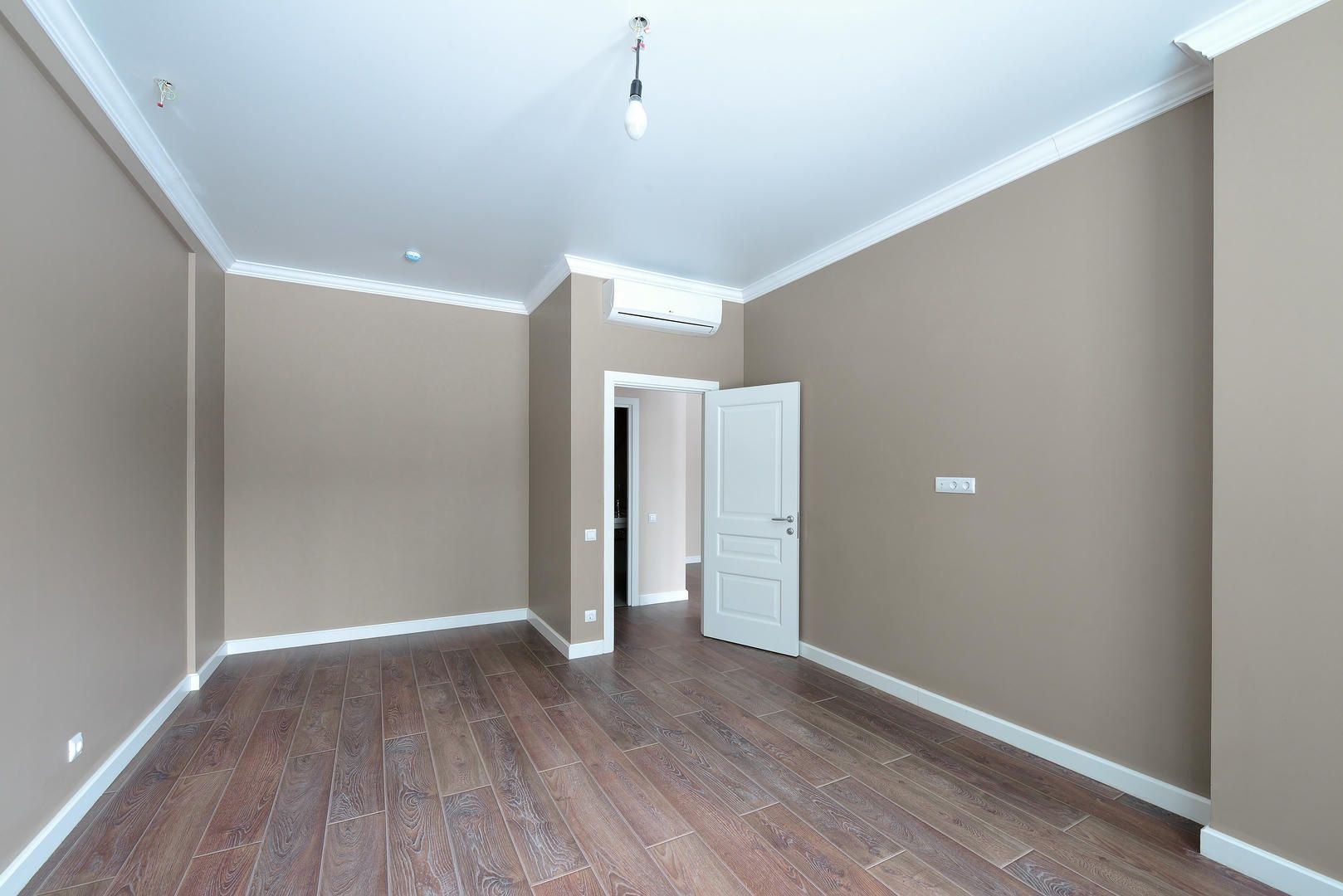An empty room with wooden floors and beige walls