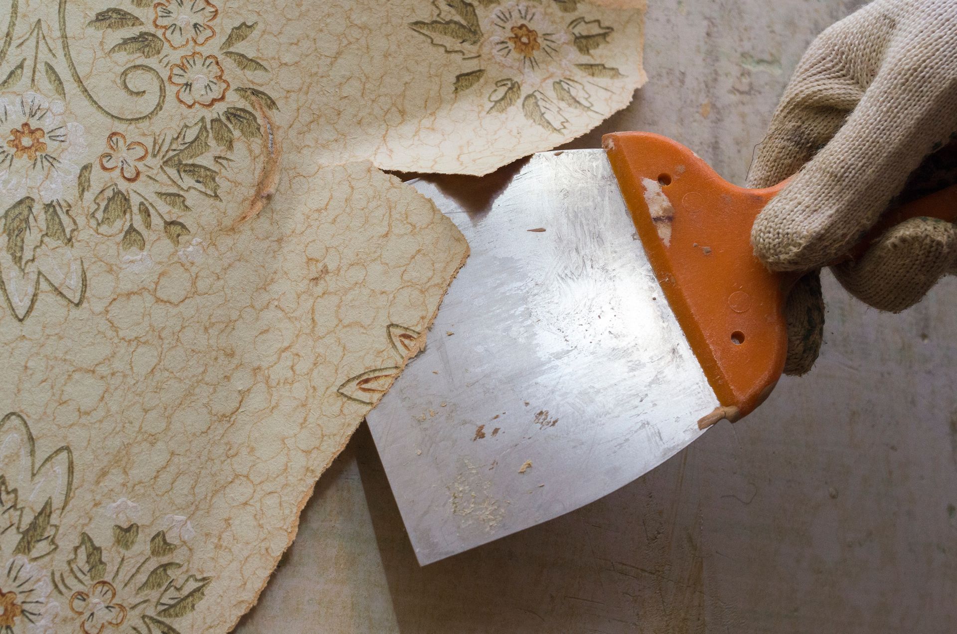 A blue tray with a brush on it is sitting on the floor next to a pile of wallpaper.