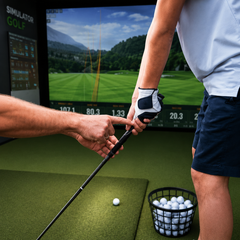 Man teaching a child how to grip a golf club on a green field.