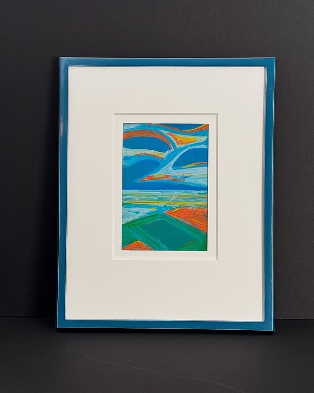 A small framed painting shows a vibrant landscape with a bright blue, swirling sky over green fields and orange patches.