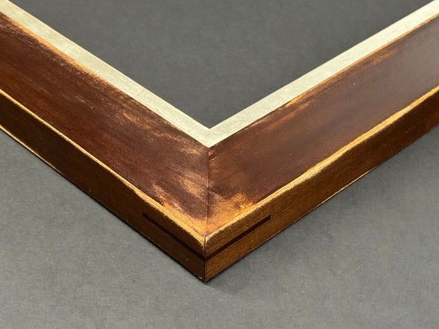A Stanley tape measure, a small hammer, and two wooden frame pieces joined at a corner with adhesive on a wooden surface.