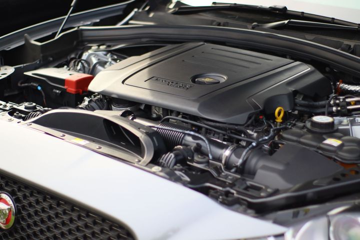 Open car hood showing a clean engine bay with a silver engine cover and visible components