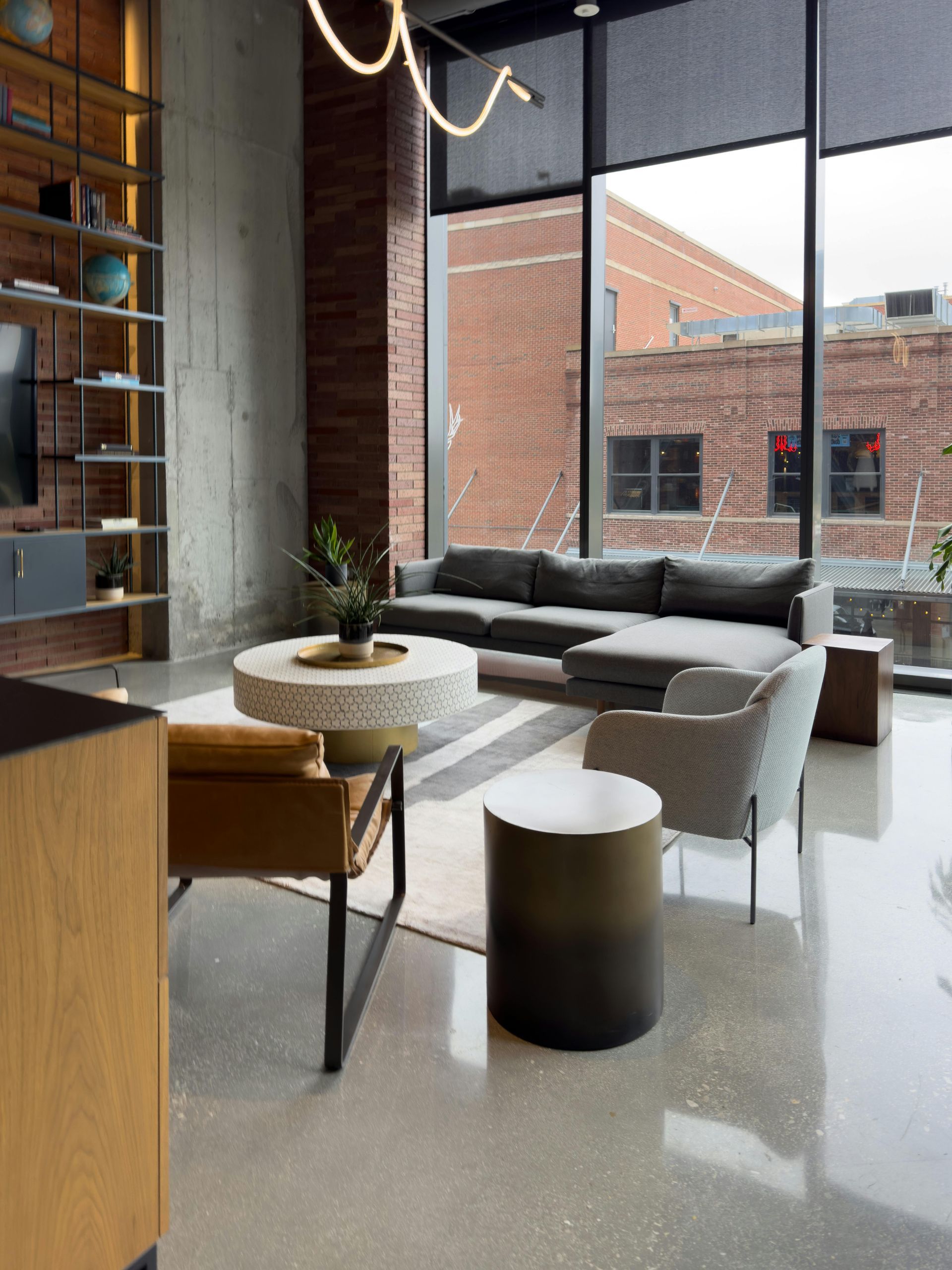 Modern living room with sectional sofa, armchairs, coffee table, and large windows with city view.