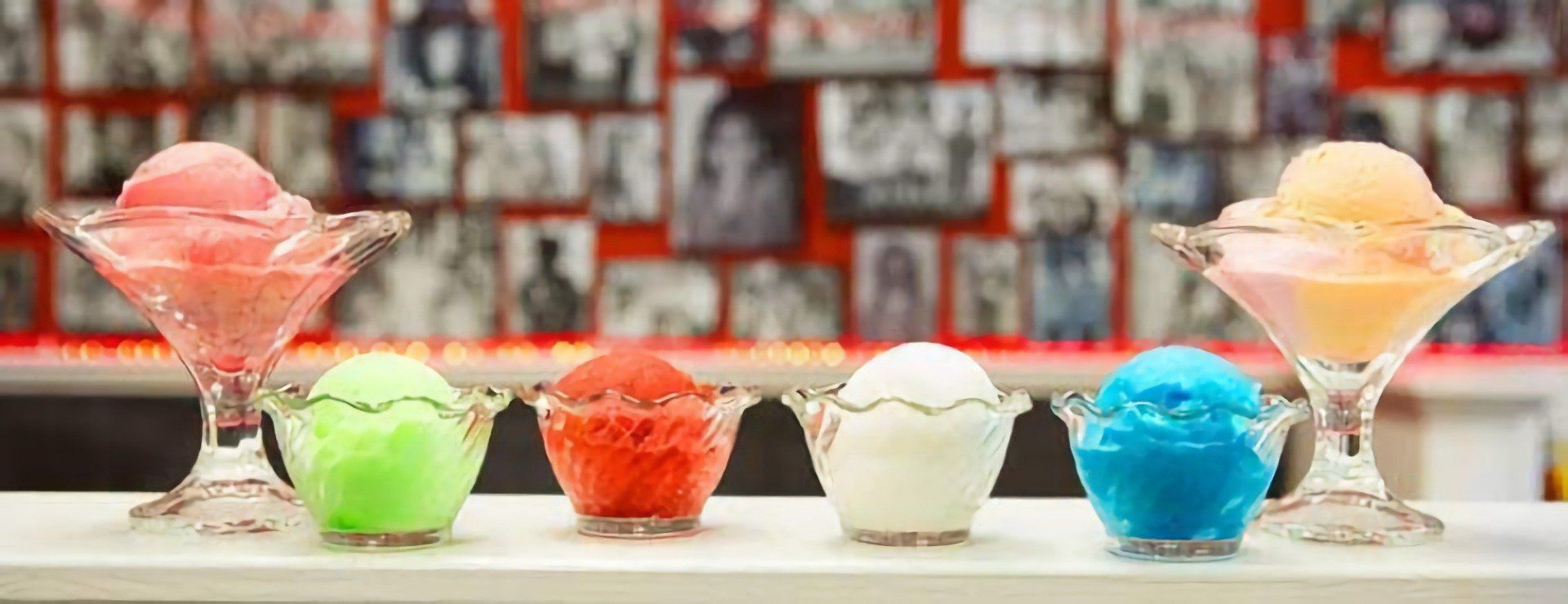 A row of bowls filled with different colored ice cream on a table.