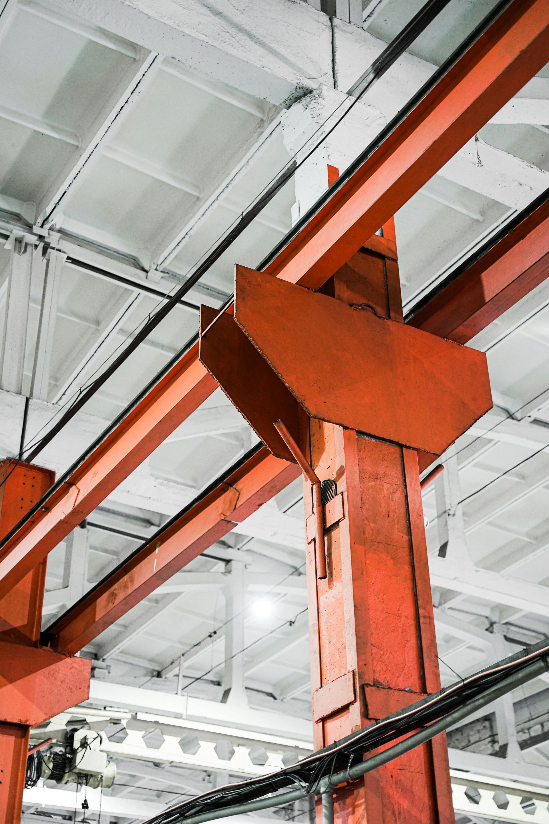 Orange steel beam and support structure inside an industrial warehouse ceiling.