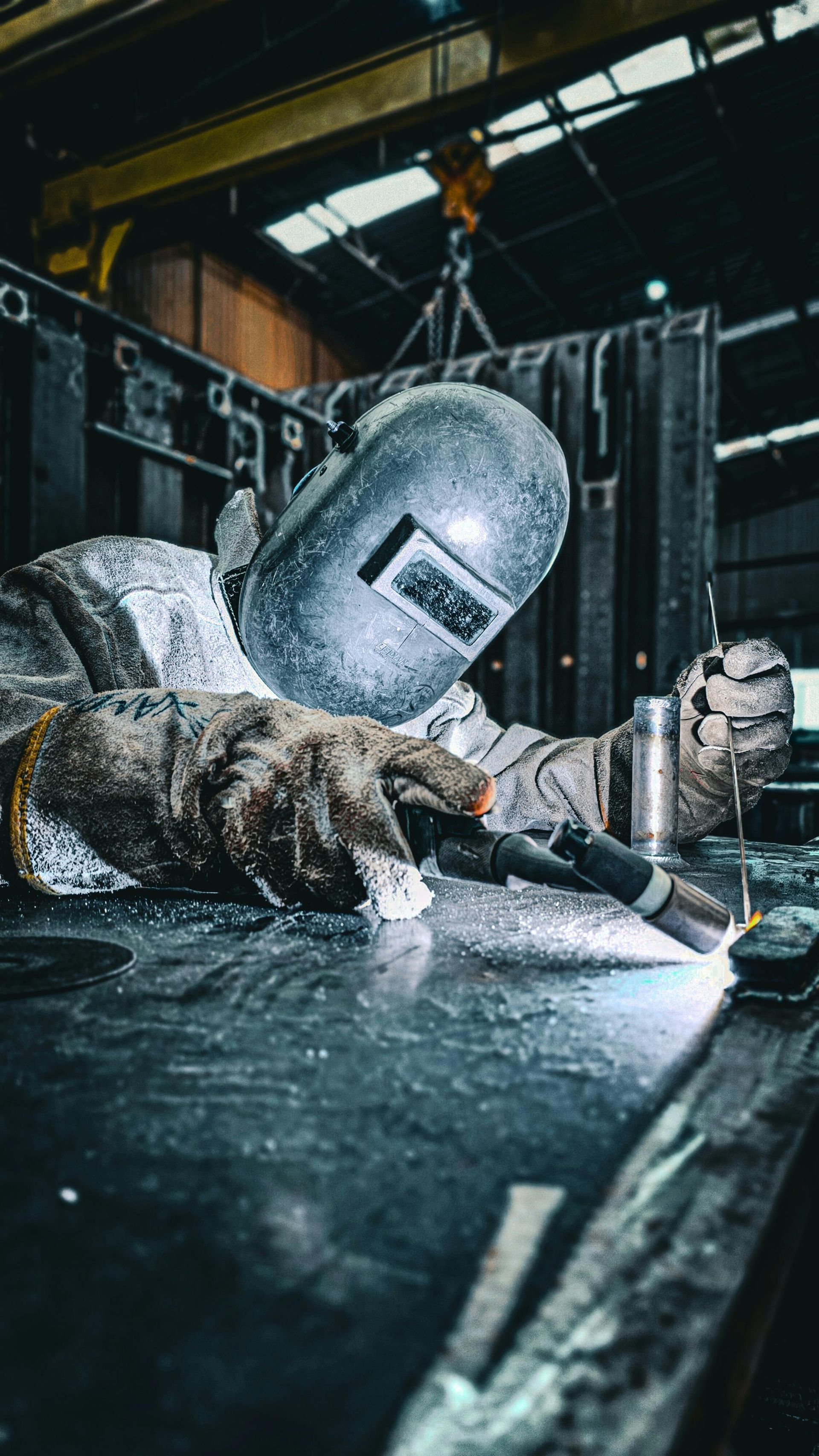 Welding worker in helmet and gloves sparks metal in an industrial workshop