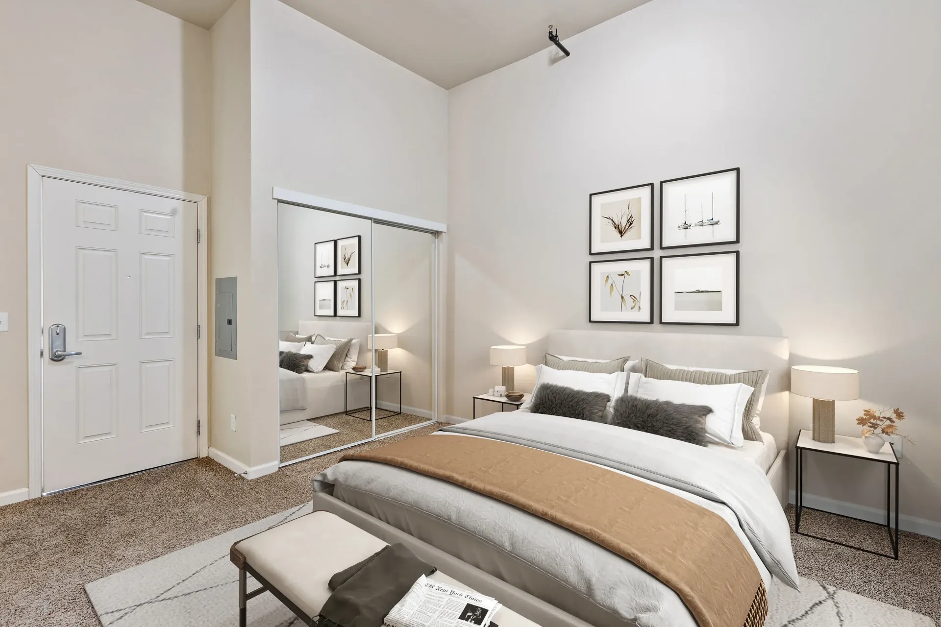 Bedroom with a large bed, mirrored sliding closet doors, and neutral decor at Volare Apartments.