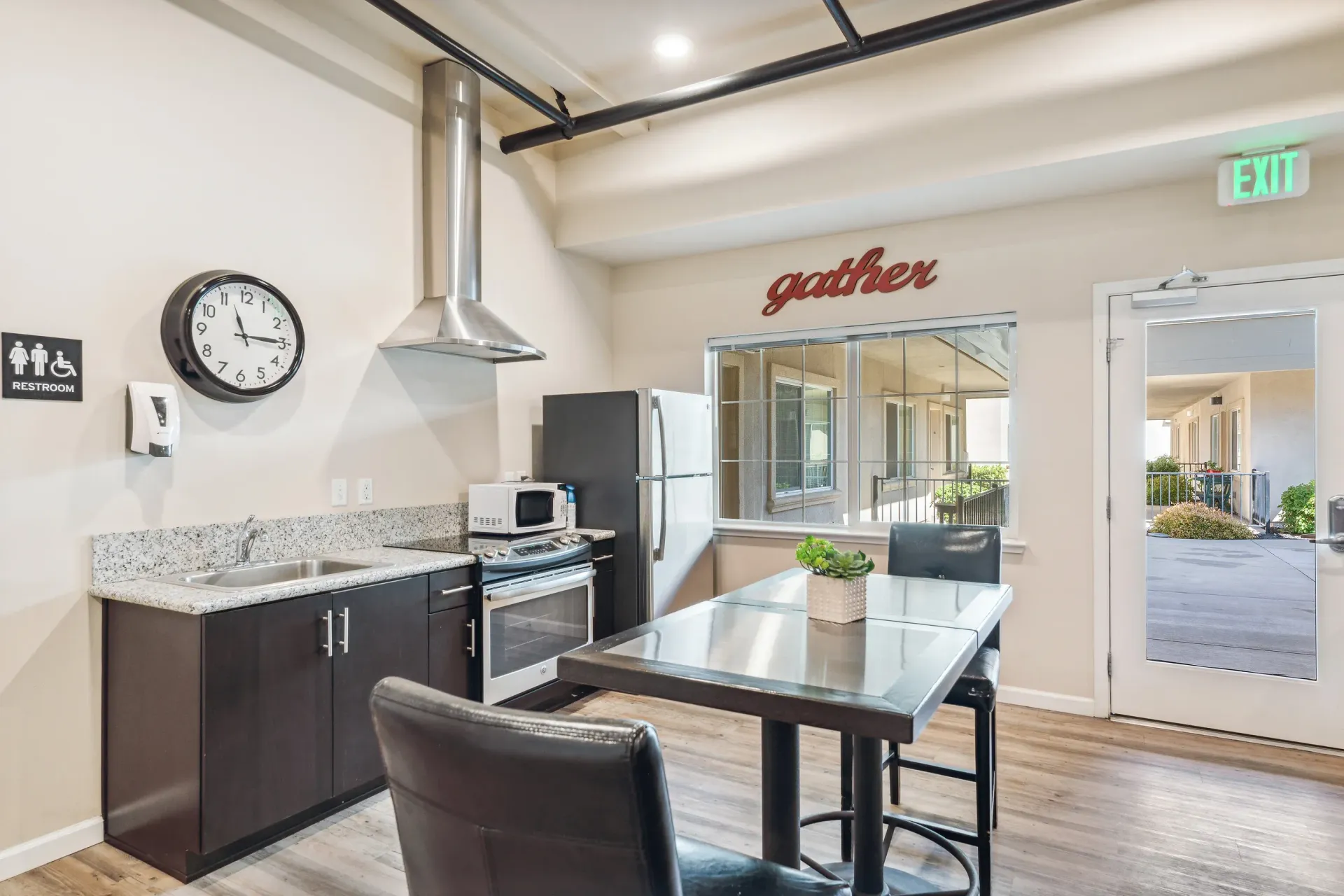 Open kitchen with granite counters, dark wood cabinets, stainless steel appliances, and a dining table at Volare Apartments.