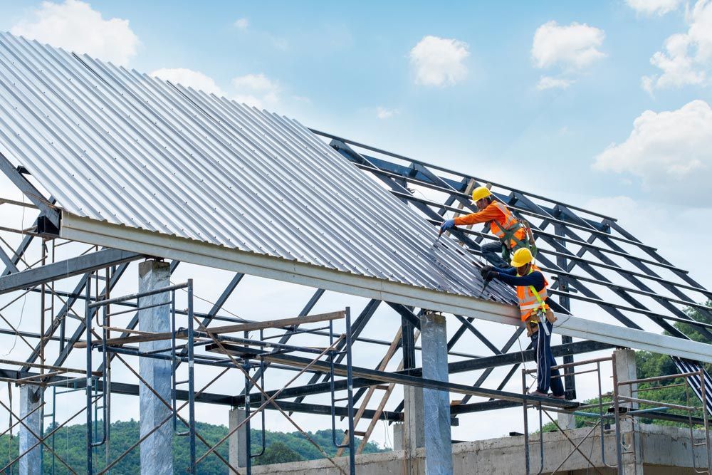 A Group of Construction Workers Are Working on the Roof of a Building — All Plumb & Gas in North Boambee Valley, NSW