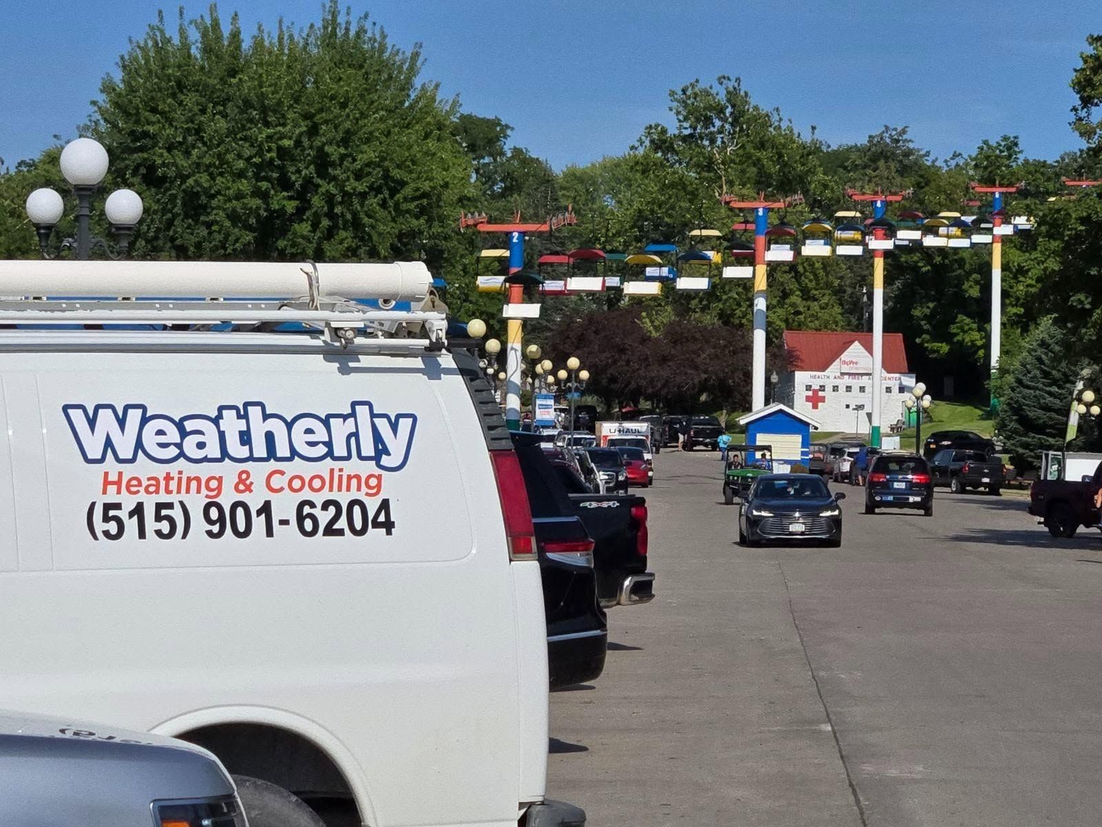 Weatherly Heating & Cooling van parked beside a street lined with cars and festive pennants