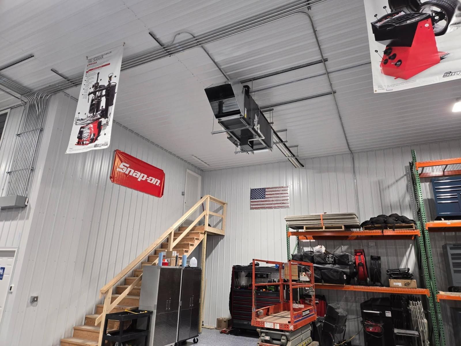 Warehouse interior with metal shelving, stairs, and a red tool cart beneath a high ceiling