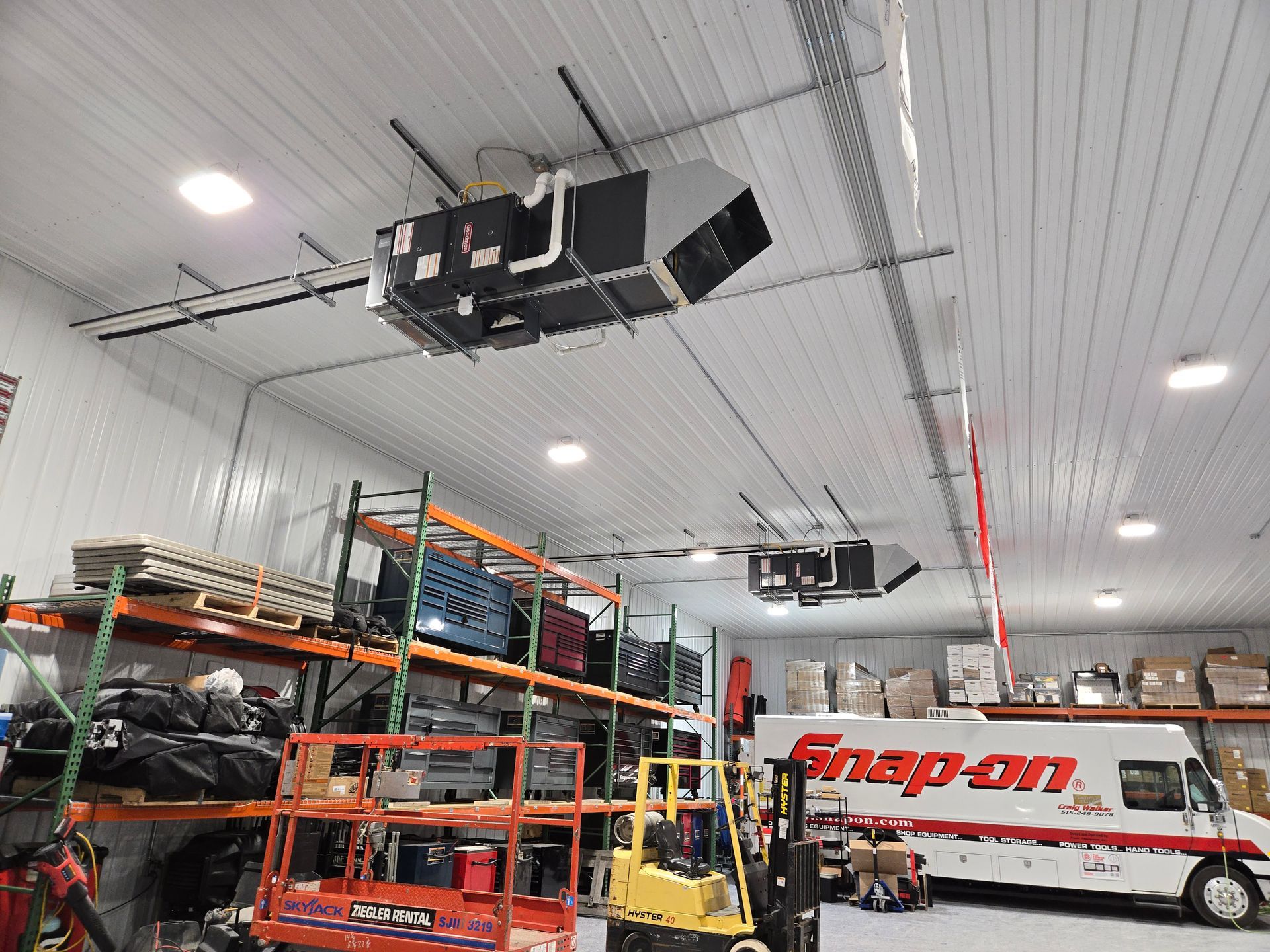 Auto repair shop interior with orange shelving, a yellow lift, and a Snap-on van under bright ceiling lights