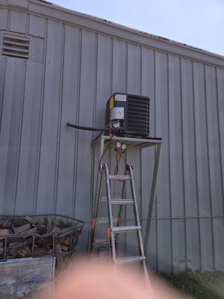 Air conditioner unit on a ladder against a gray metal building exterior