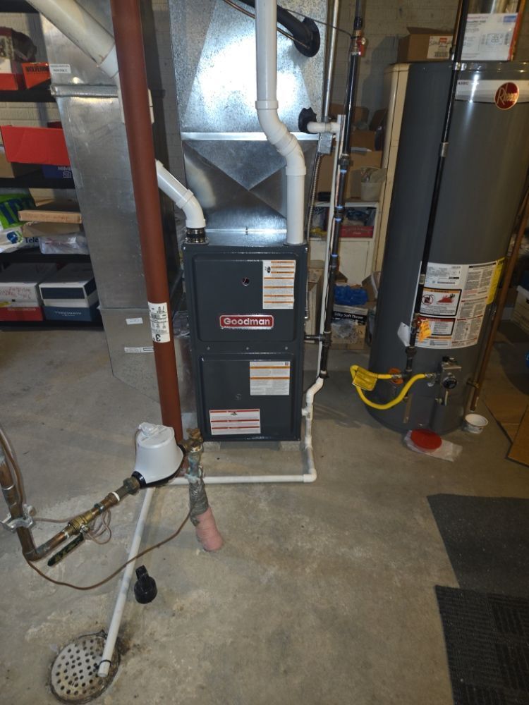 Furnace and HVAC equipment in a basement, with exposed ductwork, pipes, and concrete floor.