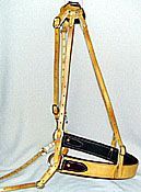Horse breast collar, tan leather with black padding, buckles, against a neutral background.