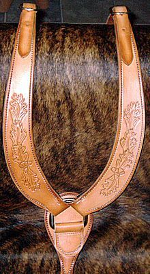Tan leather horse breast collar with floral tooling.