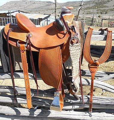 Leather Western saddle on wooden fence, brown, with stirrups and breast collar, outdoors.