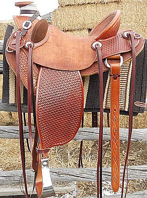Brown leather Western saddle hanging on a wooden fence.