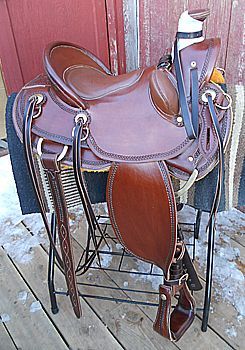 Brown leather western saddle on a black metal stand.