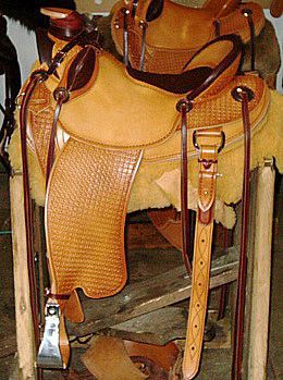 Tan and brown leather Western saddle on a wooden stand, close-up detail.