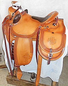 Tan leather Western saddle with cross design and saddlebag.