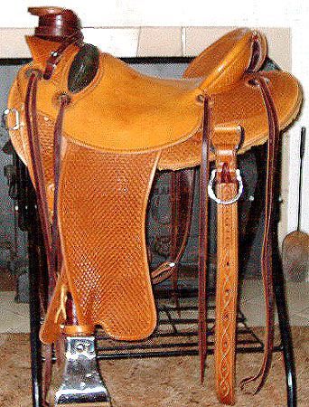 Brown leather Western saddle on a black stand, with dark brown straps, inside.