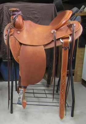 Brown leather western saddle on a black metal stand, ready for use.
