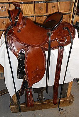 Brown leather western saddle on a wooden stand, against a background of wooden drawers.