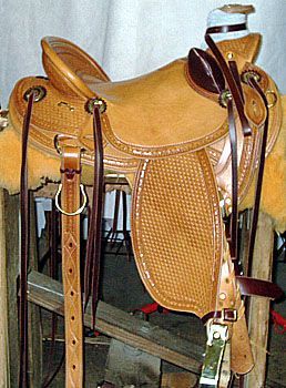 Tan leather Western saddle with tooling, stirrups, and a fleece lining on a wooden frame.