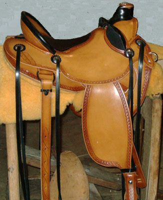 Brown leather Western saddle with black trim, resting on a wooden stand.