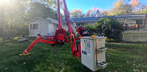 A red bucket truck on a lawn near a house. The sun shines brightly.