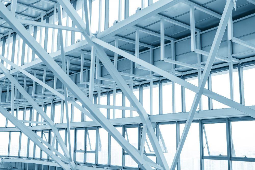 Blue steel framework of a building under construction, with intersecting beams and open windows.