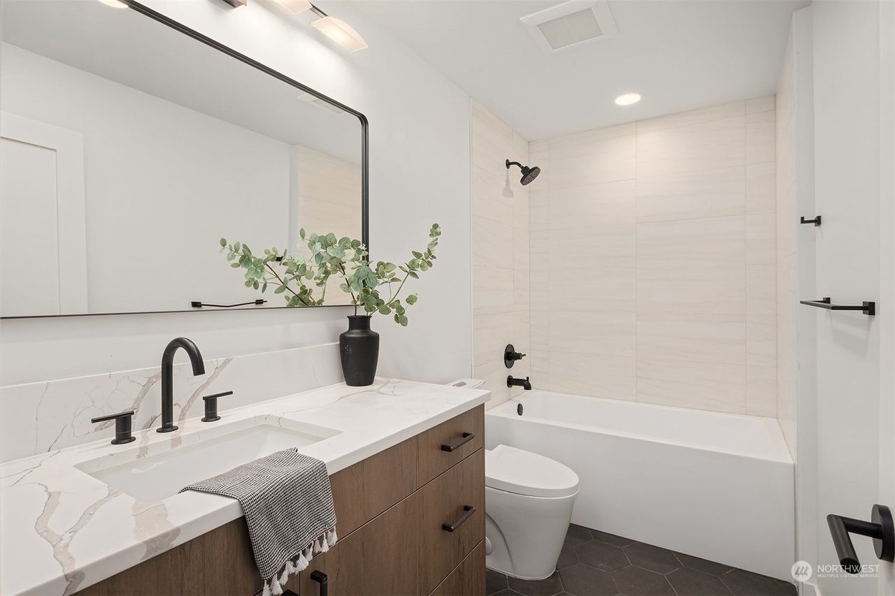 A bathroom with a sink , toilet , bathtub and mirror.