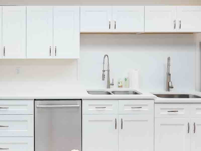 A kitchen with white cabinets , stainless steel appliances , a sink , and a dishwasher.