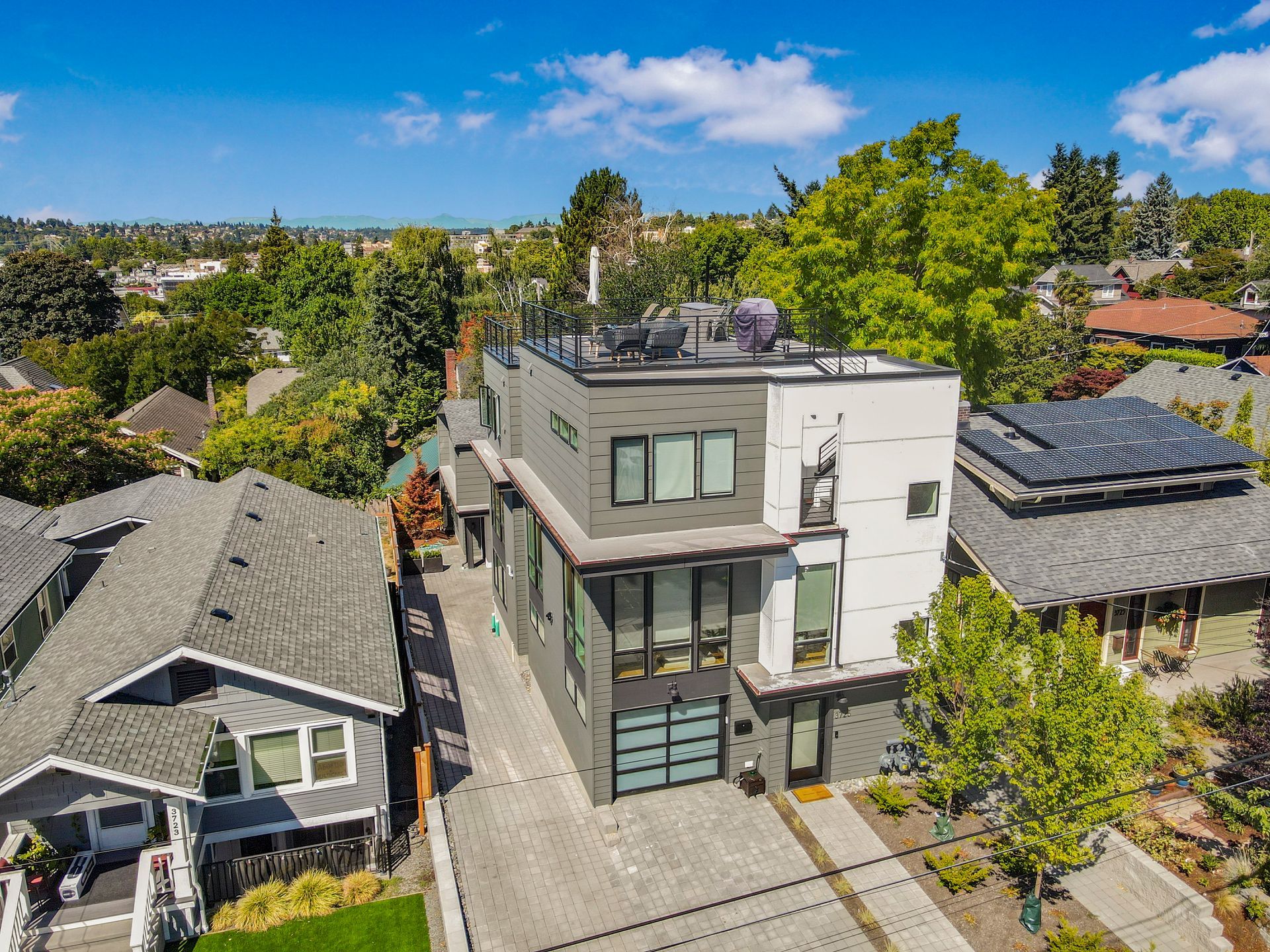 An aerial view of a house with solar panels on the roof surrounded by houses.