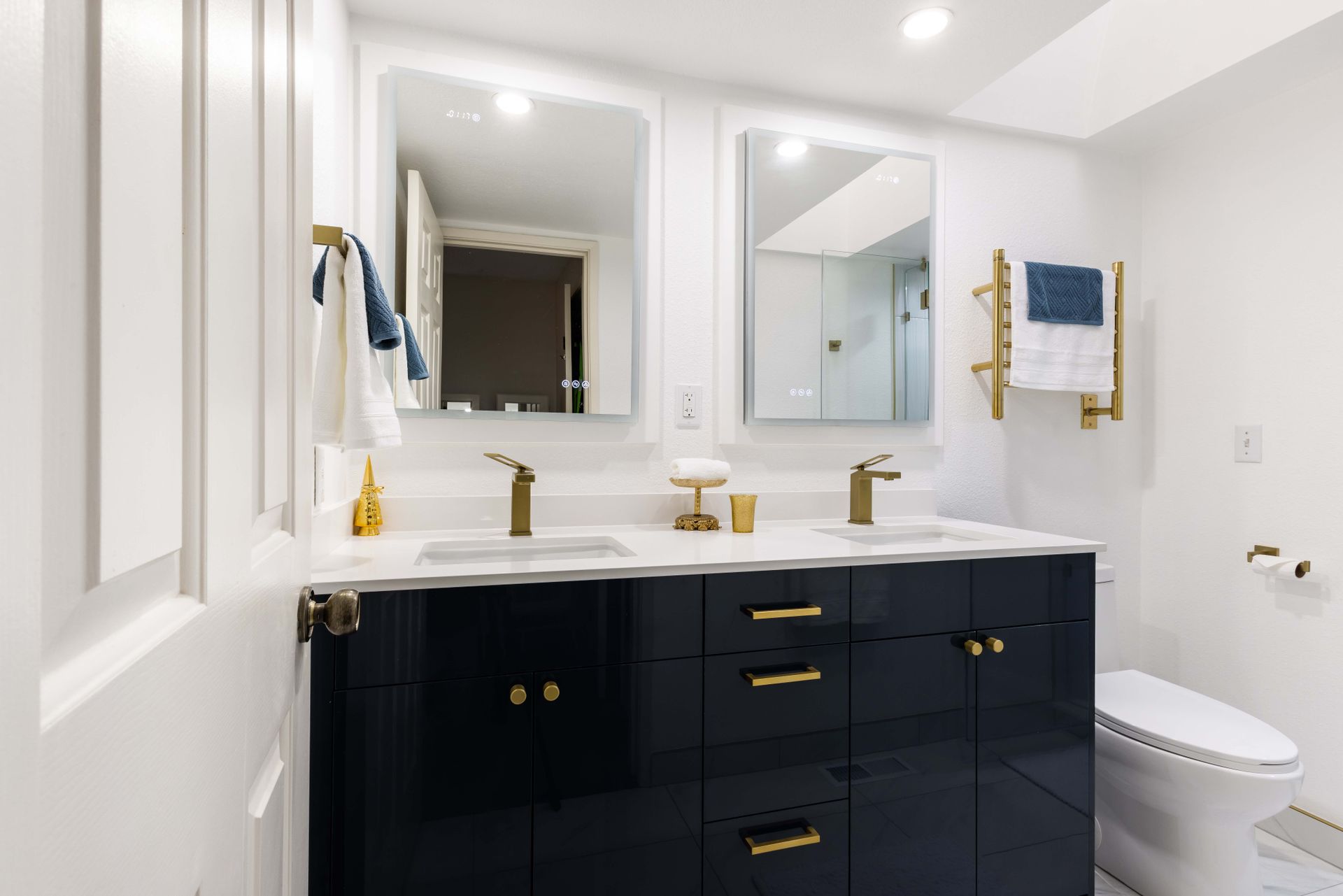 A bathroom with two sinks , a toilet and two mirrors.