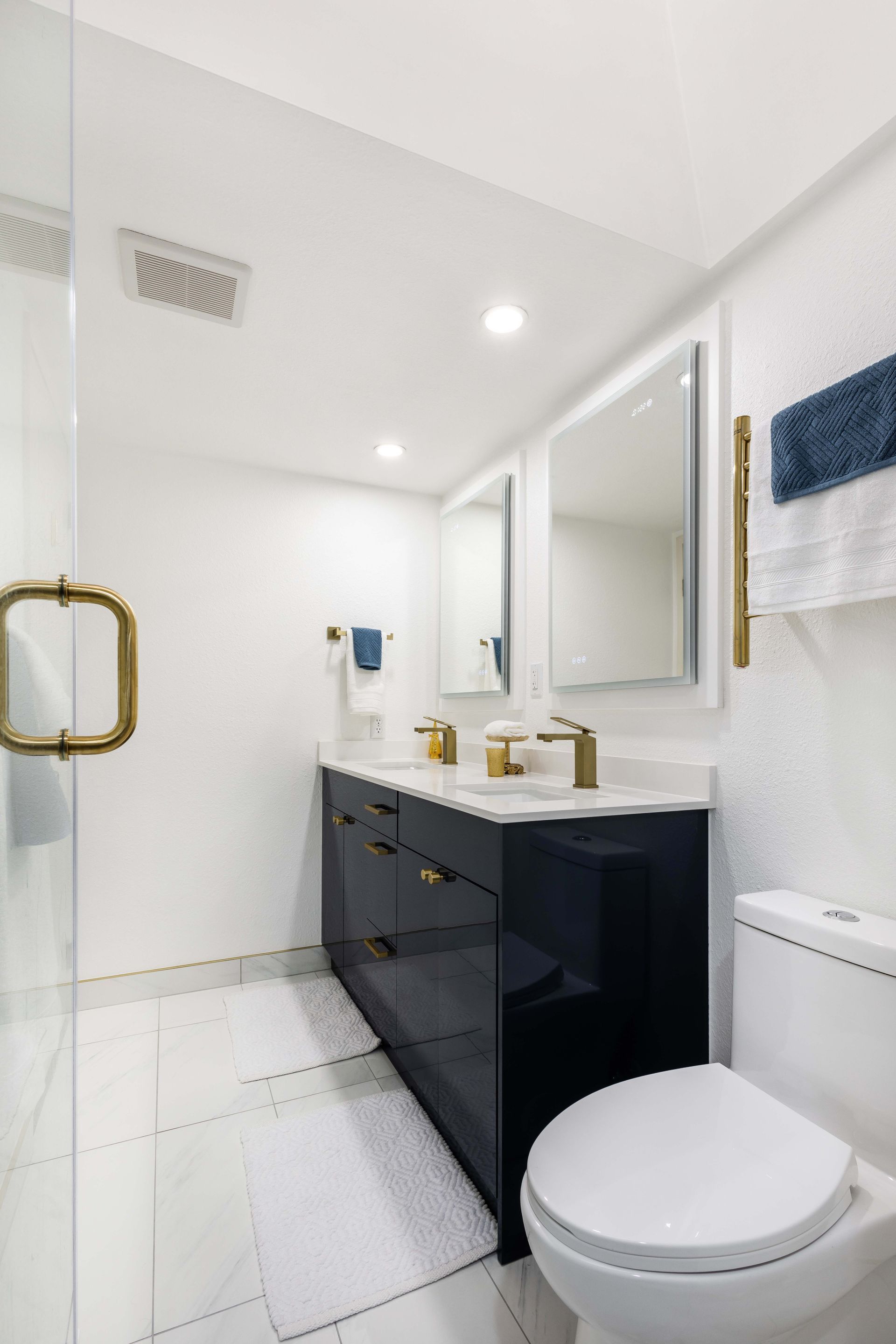 A bathroom with a toilet , sink , mirrors and a walk in shower.