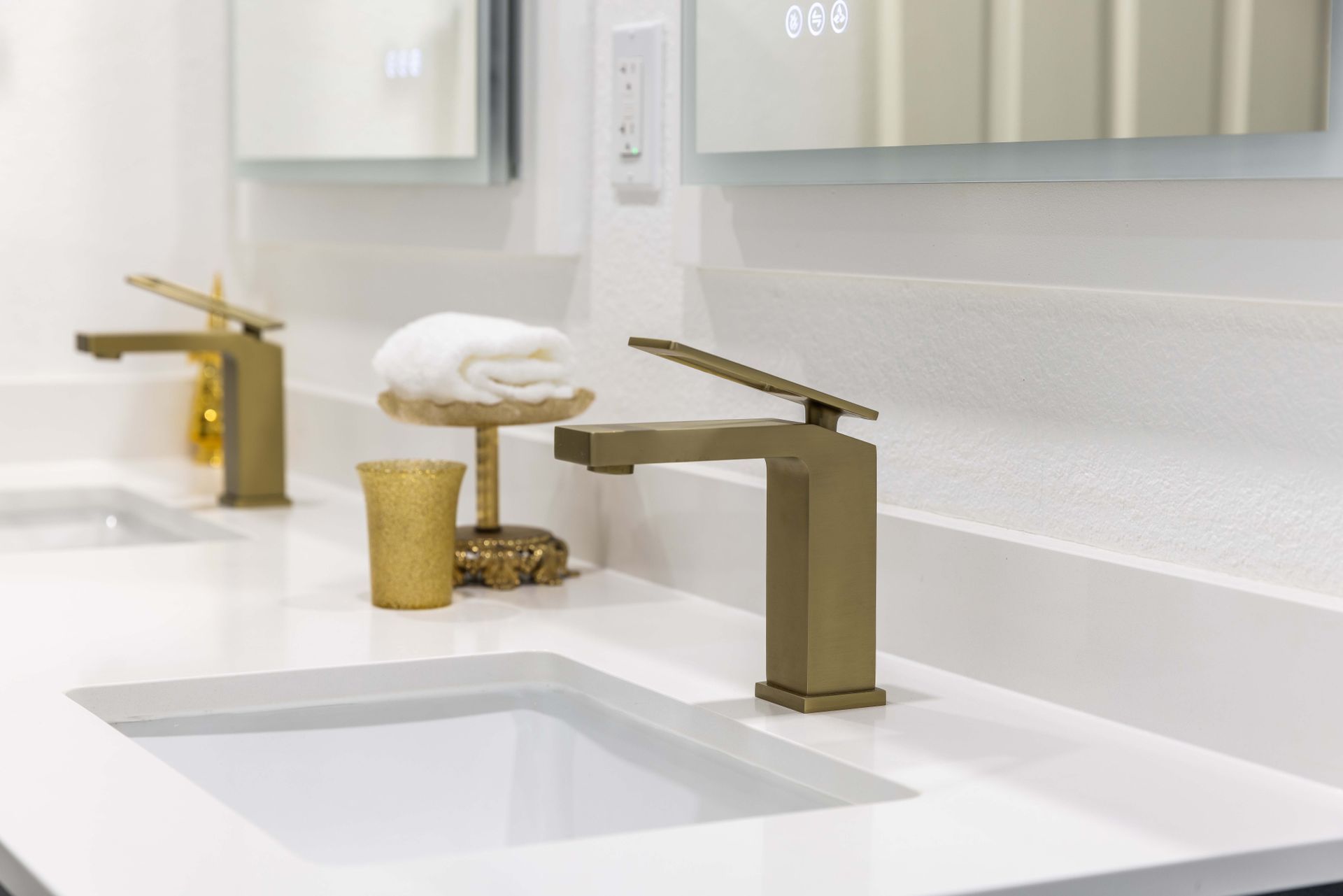 There are two sinks in the bathroom with gold faucets.