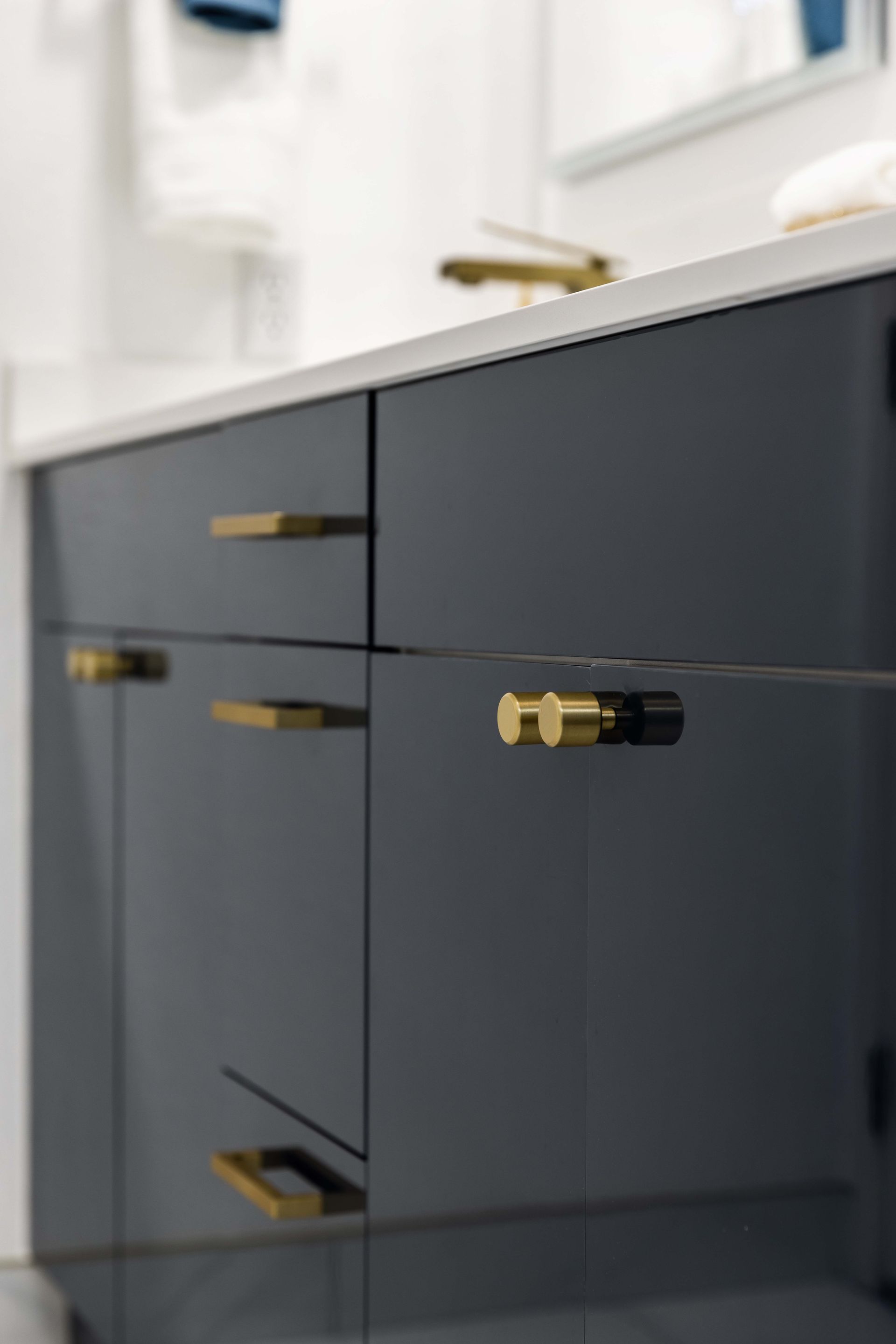 A bathroom vanity with black cabinets and gold handles.